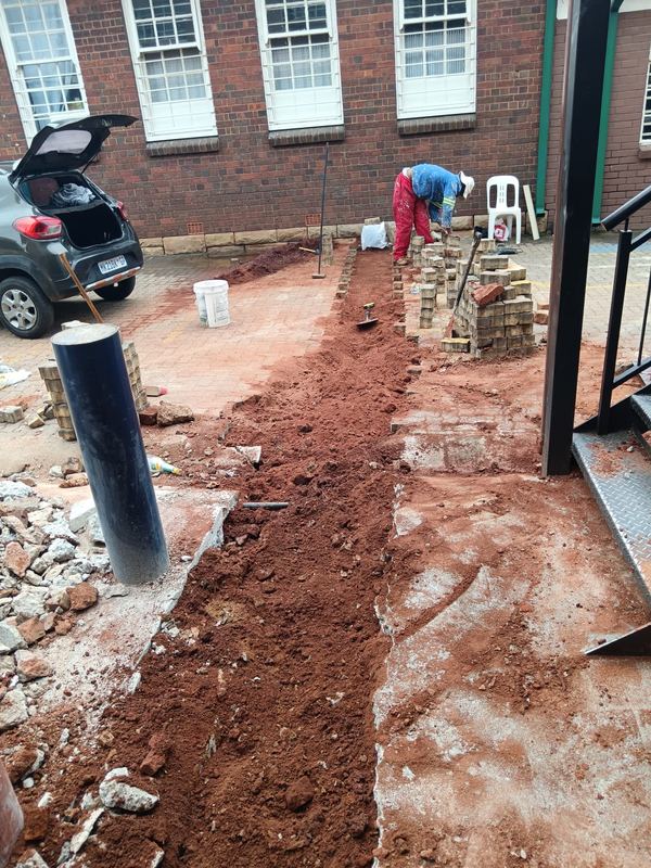 Service trench excavated alongside a brick building
