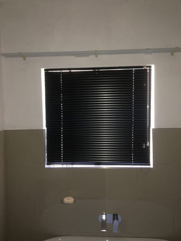 Black venetian blind over a bath