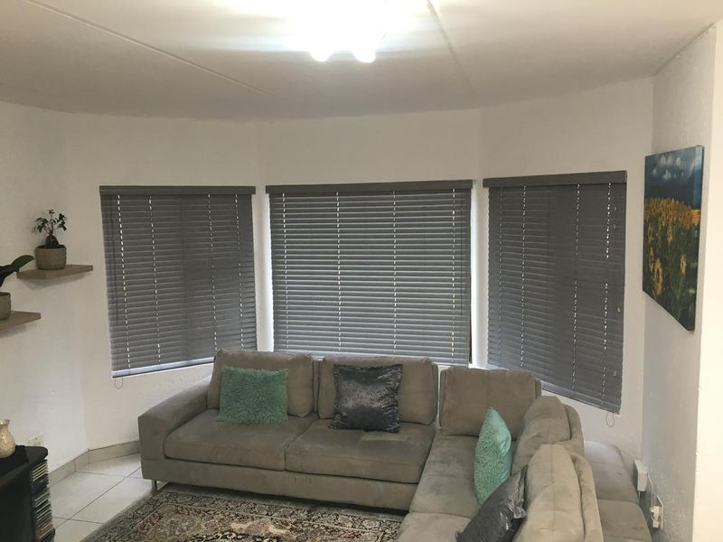 Grey venetian blinds across a three-window bay