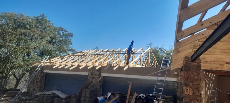 Timber roof trusses set out over a garage with stone pillars