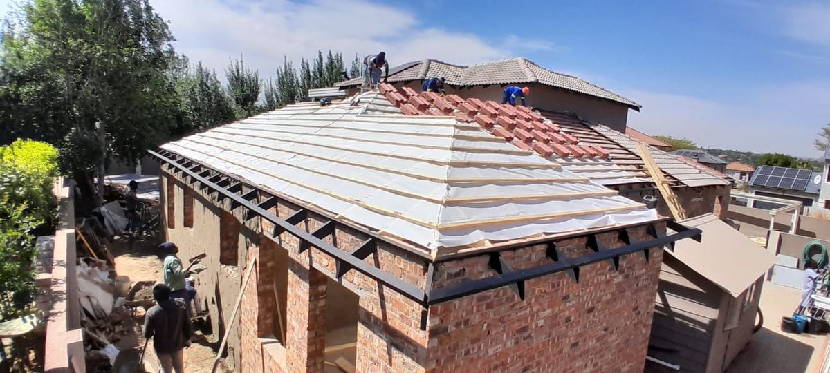Roof underlay, battens and concrete tiles being laid over a brick extension