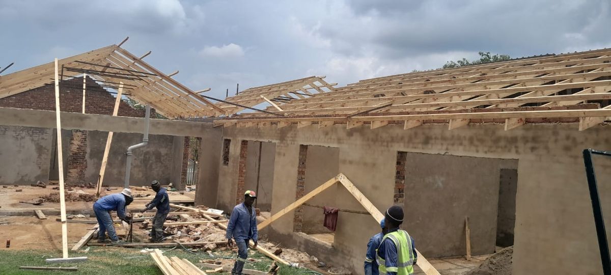 Roof timbers going up across two wings of a plastered building