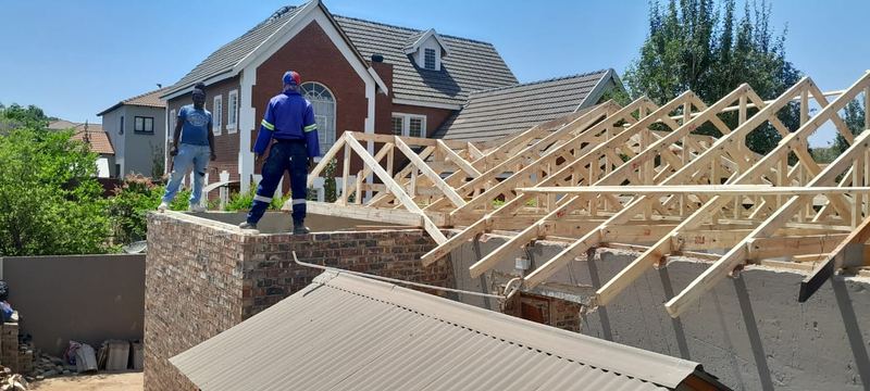 Prefabricated roof trusses craned into place on a brick extension